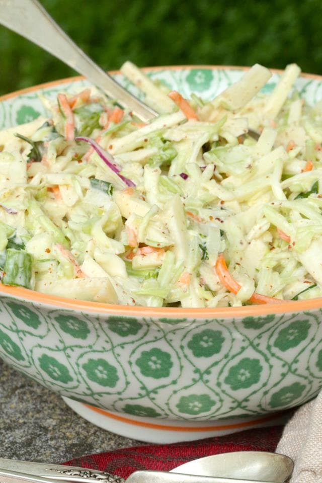 Coleslaw with Mustard and Apples in large colorful bowl with spoon
