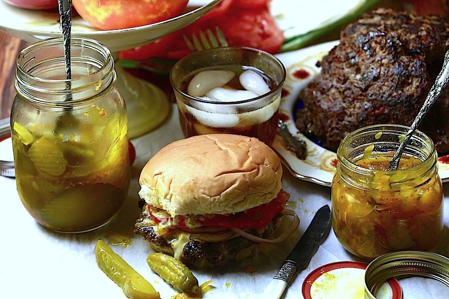 venison burger recipe - burger in bun with pickles, served with iced tea on table
