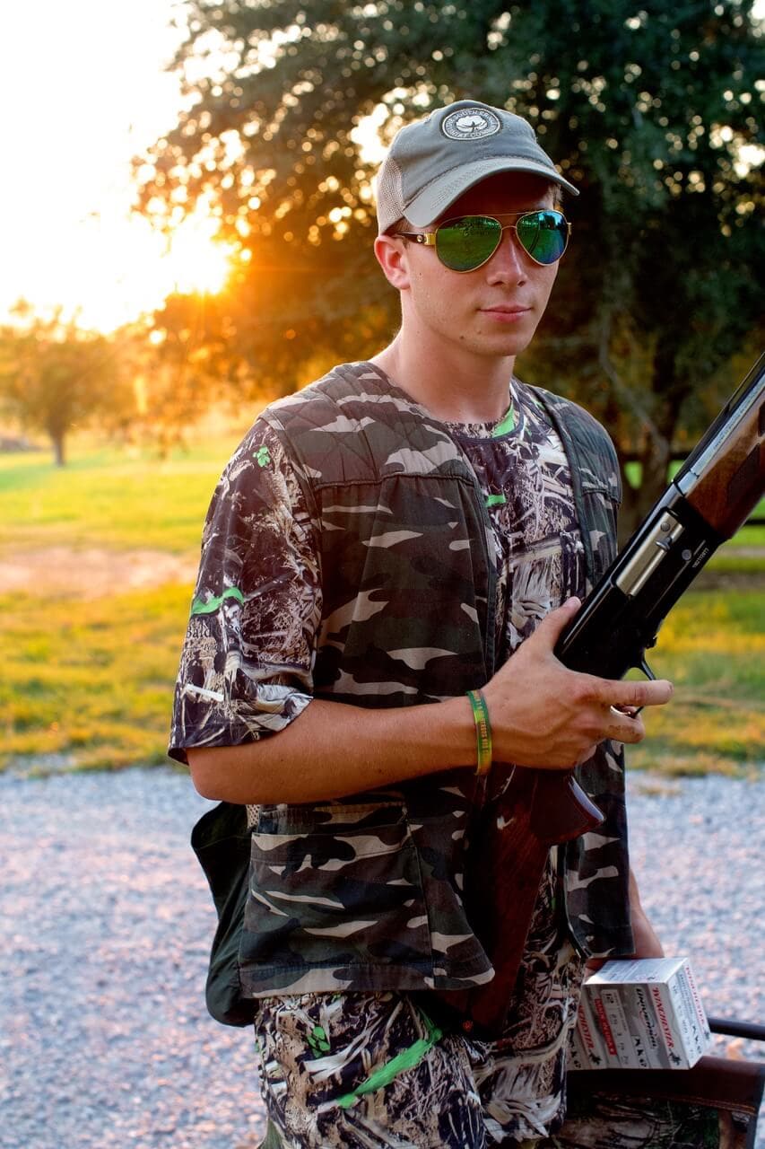 Stacy Lyn's son decked out in full camo and hunting gear holding a shotgun in preparation for the dove hunt