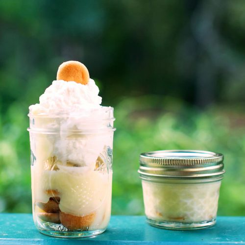 Banana pudding in mason jars, topped with vanilla wafers and whipped cream