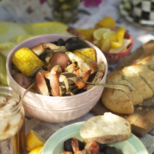 Clam bake scene featuring seafood and corn on a newspapered table.