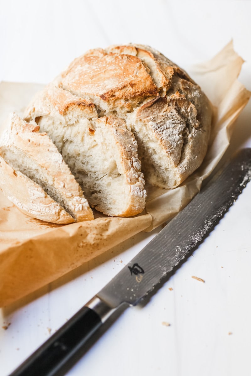 Bright photo of fresh artisan bread on parchment paper on white background