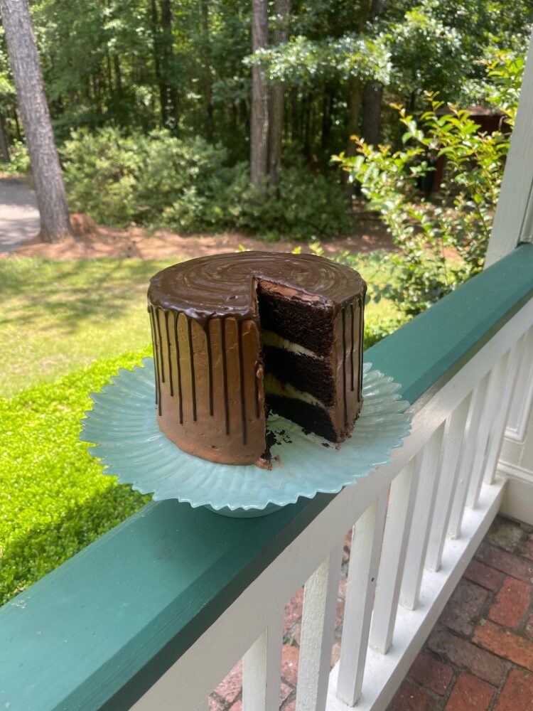 cappuccino chocolate cake with chocolate ganache, on blue plate resting on front porch railing