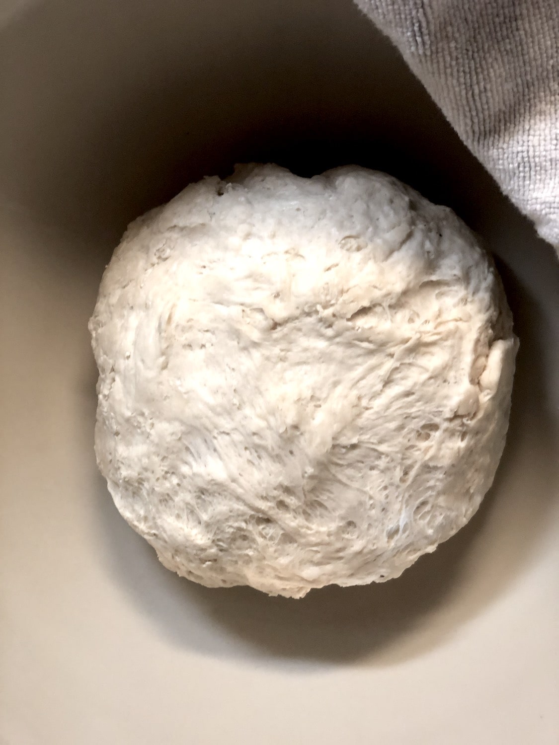 Dough formed into a ball in the middle of a bowl