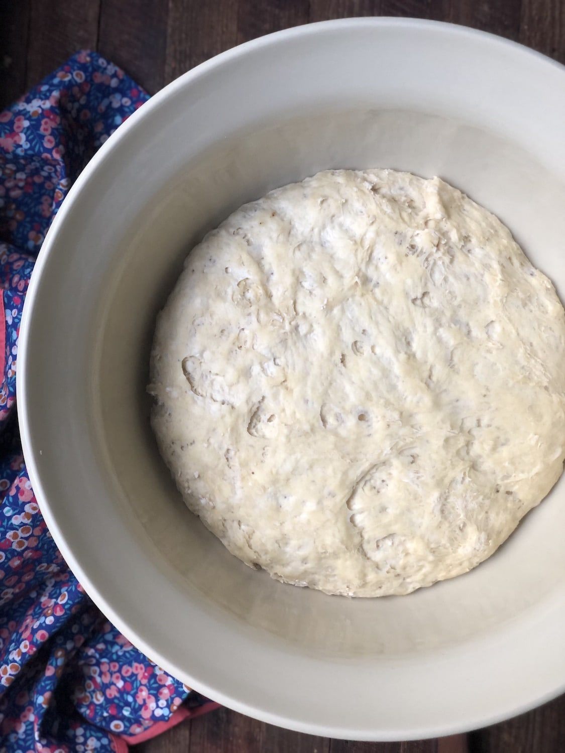Dough that has risen overnight in a bowl with a purple vintage napkin