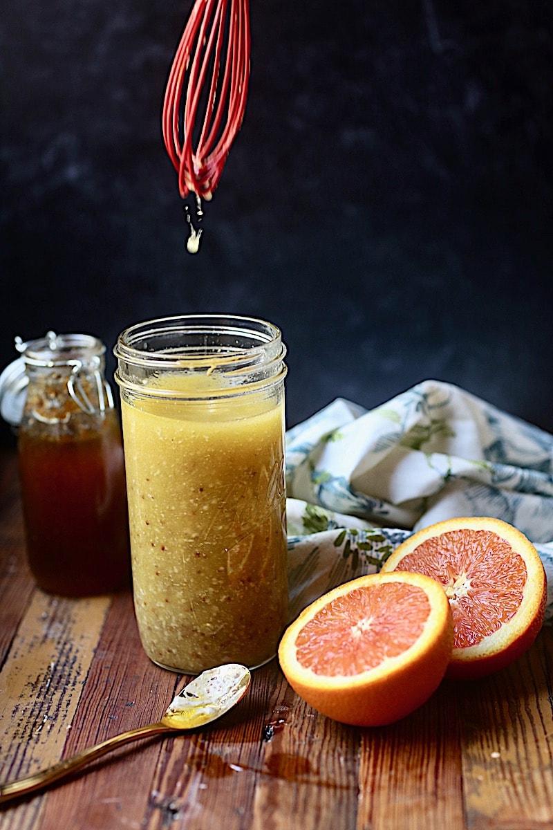 Vinaigrette in mason jar with cut oranges and jar of honey