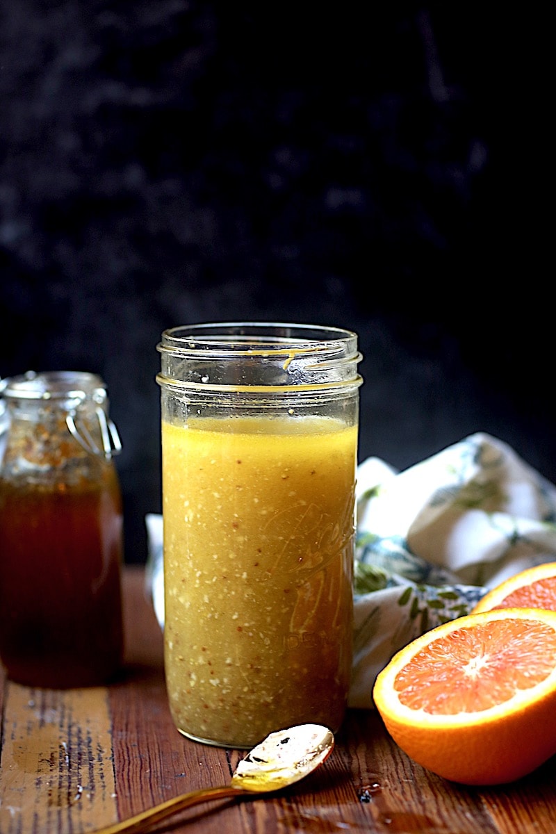 Vinaigrette with honey and oranges on wood with black background