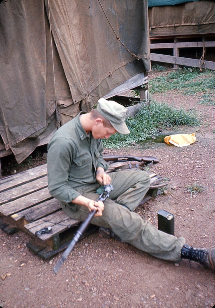 A photo of my dad taking apart and cleaning gun alone. Memorial Day reflections on war, PTSD, and freedom.