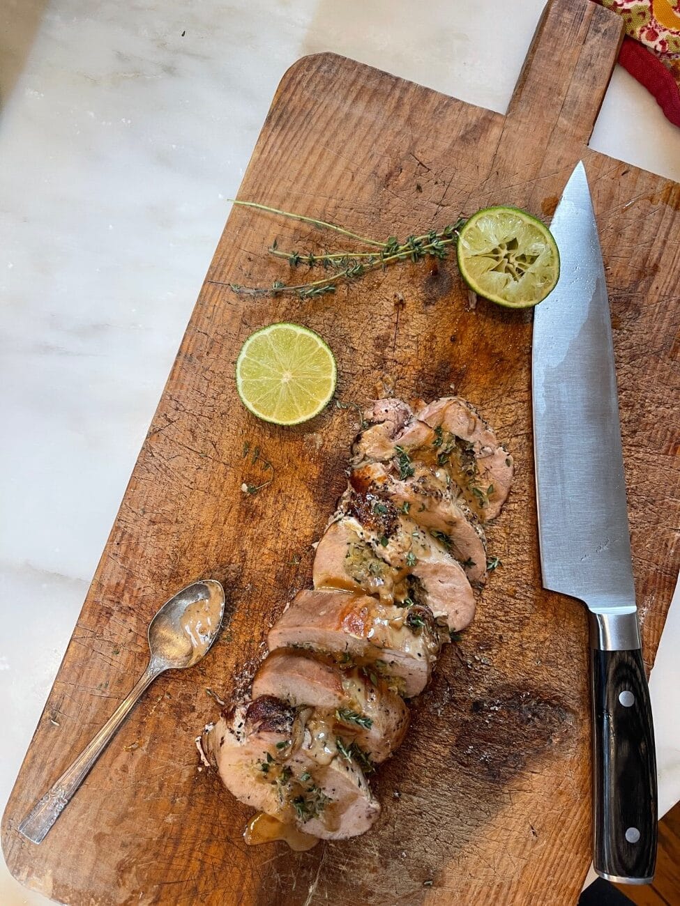 stuffed turkey breast cooked and sliced on wooden cutting board with rounds of fresh lime