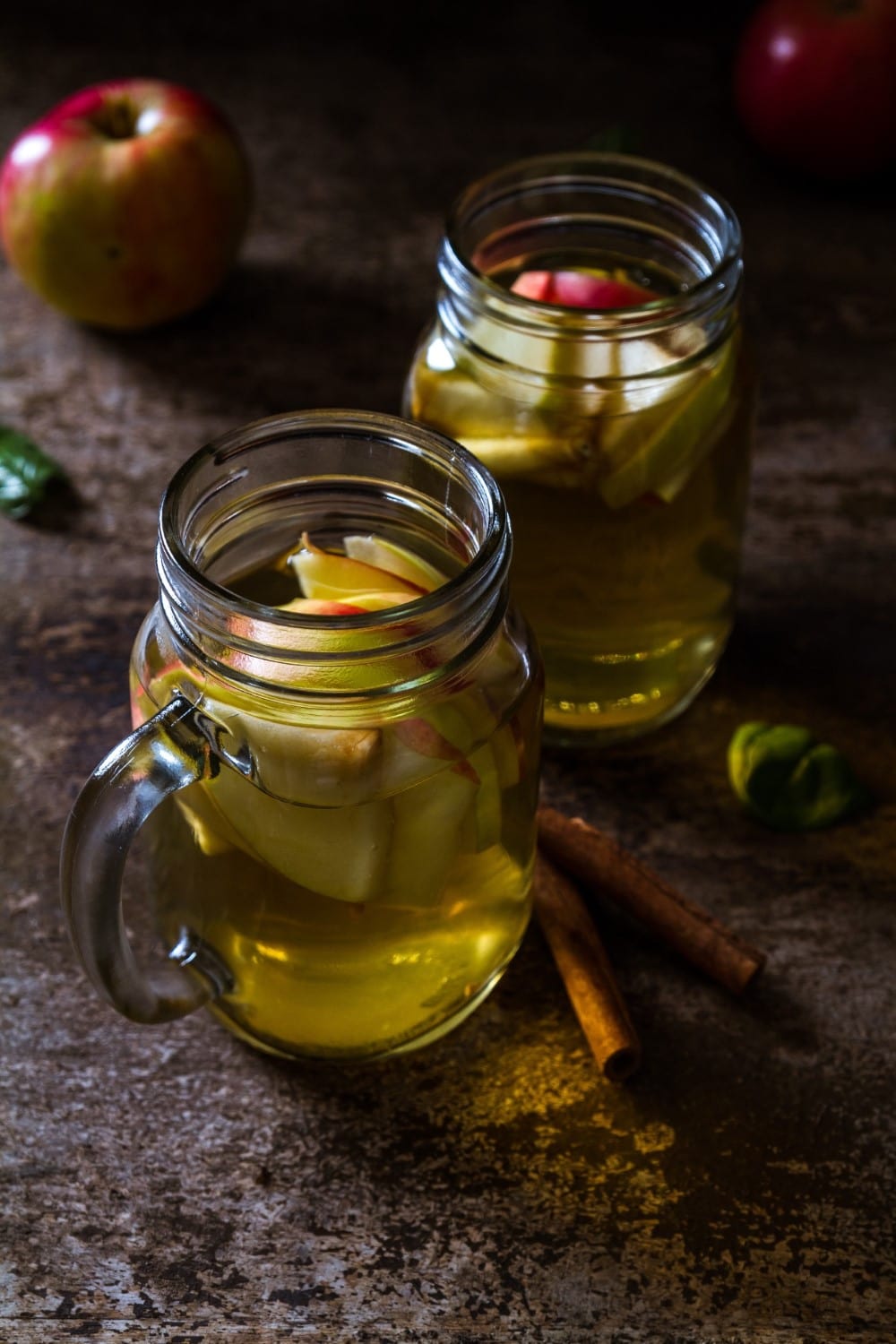 apple cider vinegar beverage with sliced apples in mason jars